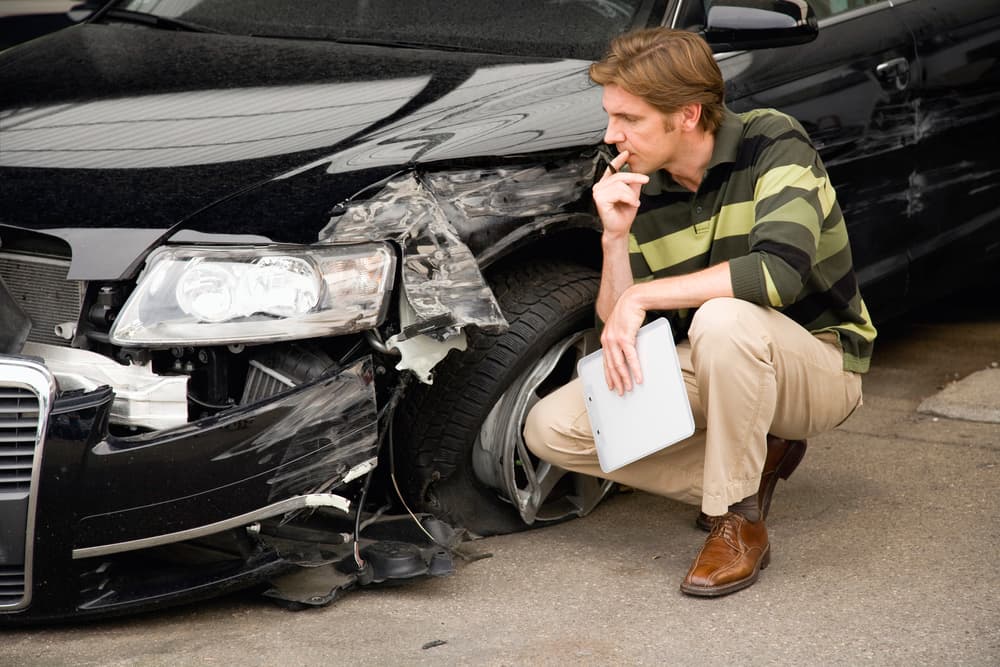 Focused claims adjuster inspecting car damage with precision for accurate assessment.