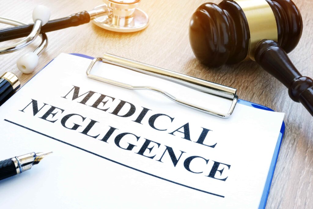 Medical negligence document on clipboard with judge&rsquo;s gavel and stethoscope.