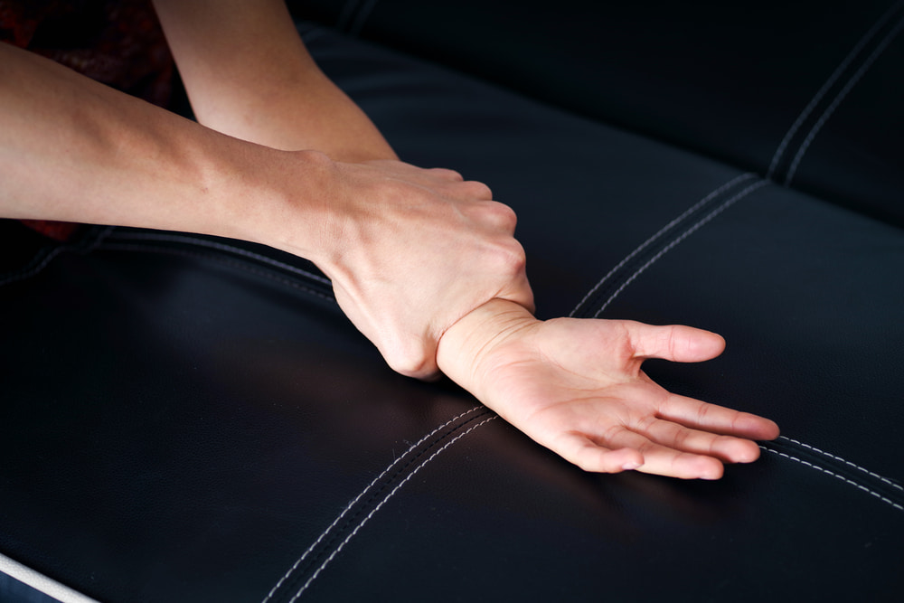 Attacker's hand gripping a person's wrist against a dark background