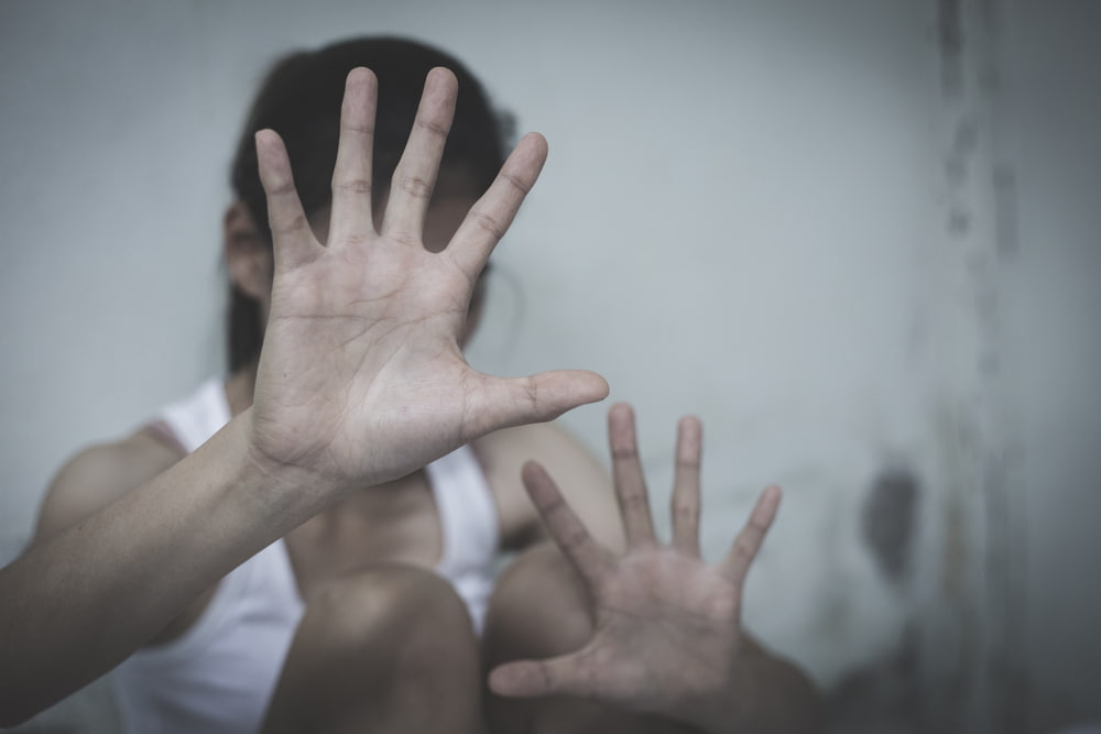Frightened woman raising both hands in a defensive stop gesture